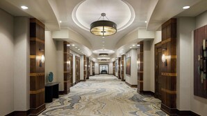 A long, well-lit hallway with patterned carpet, wooden paneling, and multiple doors. - Marriott Denver South at Park Meadows (Lone Tree)