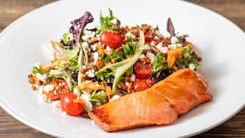 A plate with a salad and a piece of salmon.