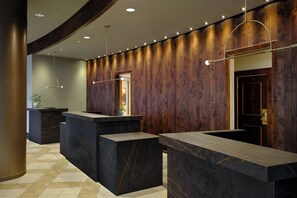 A reception area with marble counters, wooden paneling, and pendant lighting.