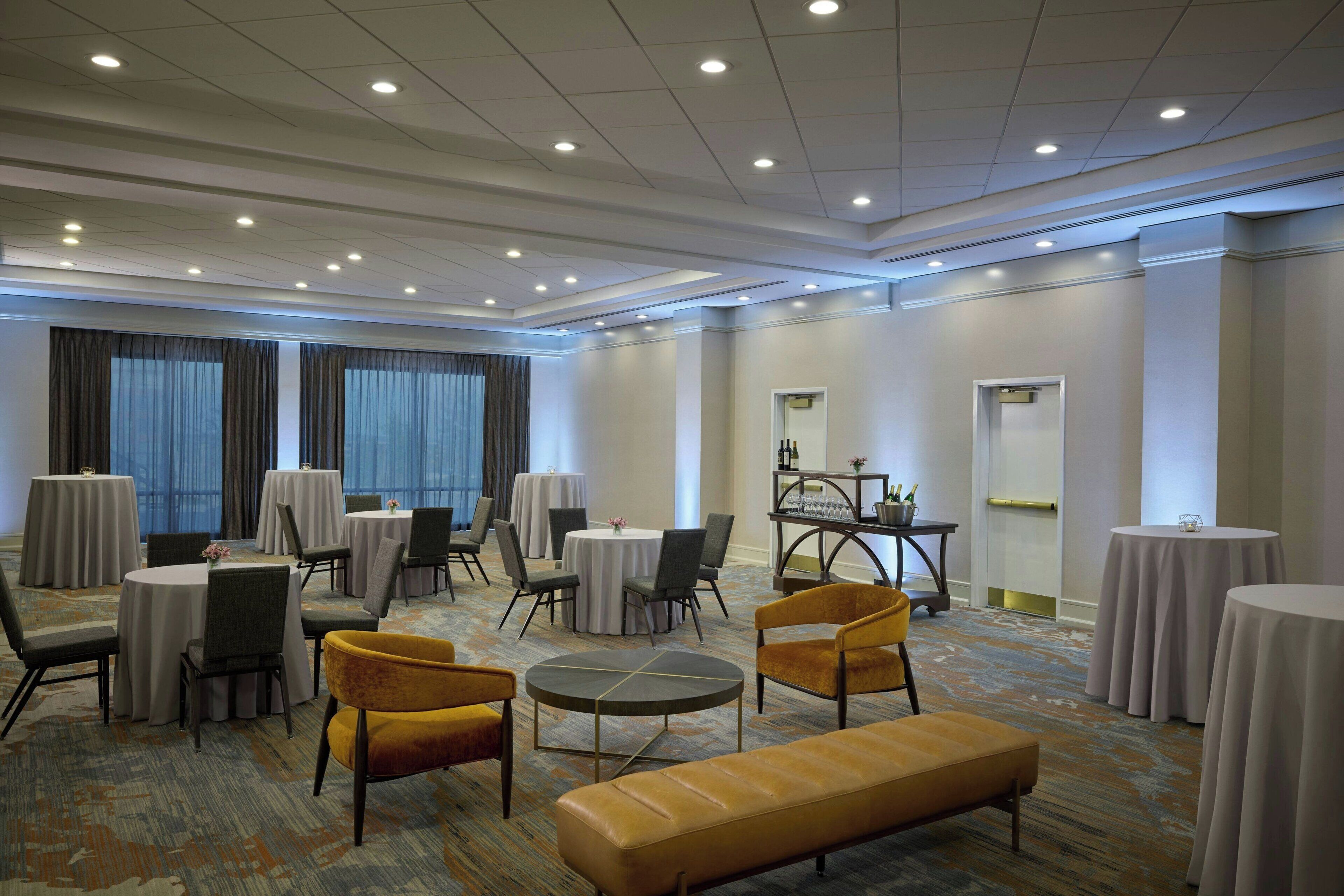 A spacious conference room with multiple tables and chairs, a central round table, and a sofa.