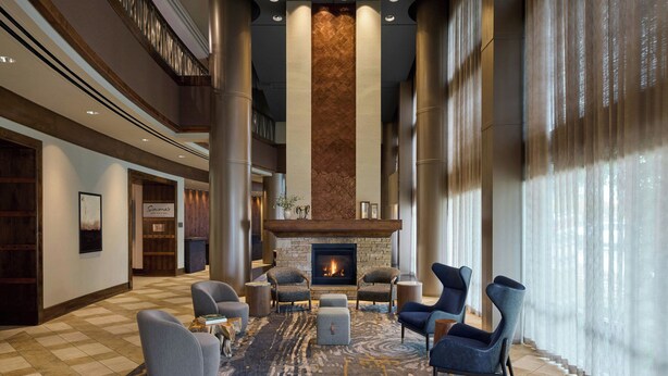 A spacious lobby with a fireplace, comfortable seating, and large windows. - Marriott Denver South at Park Meadows (Lone Tree)