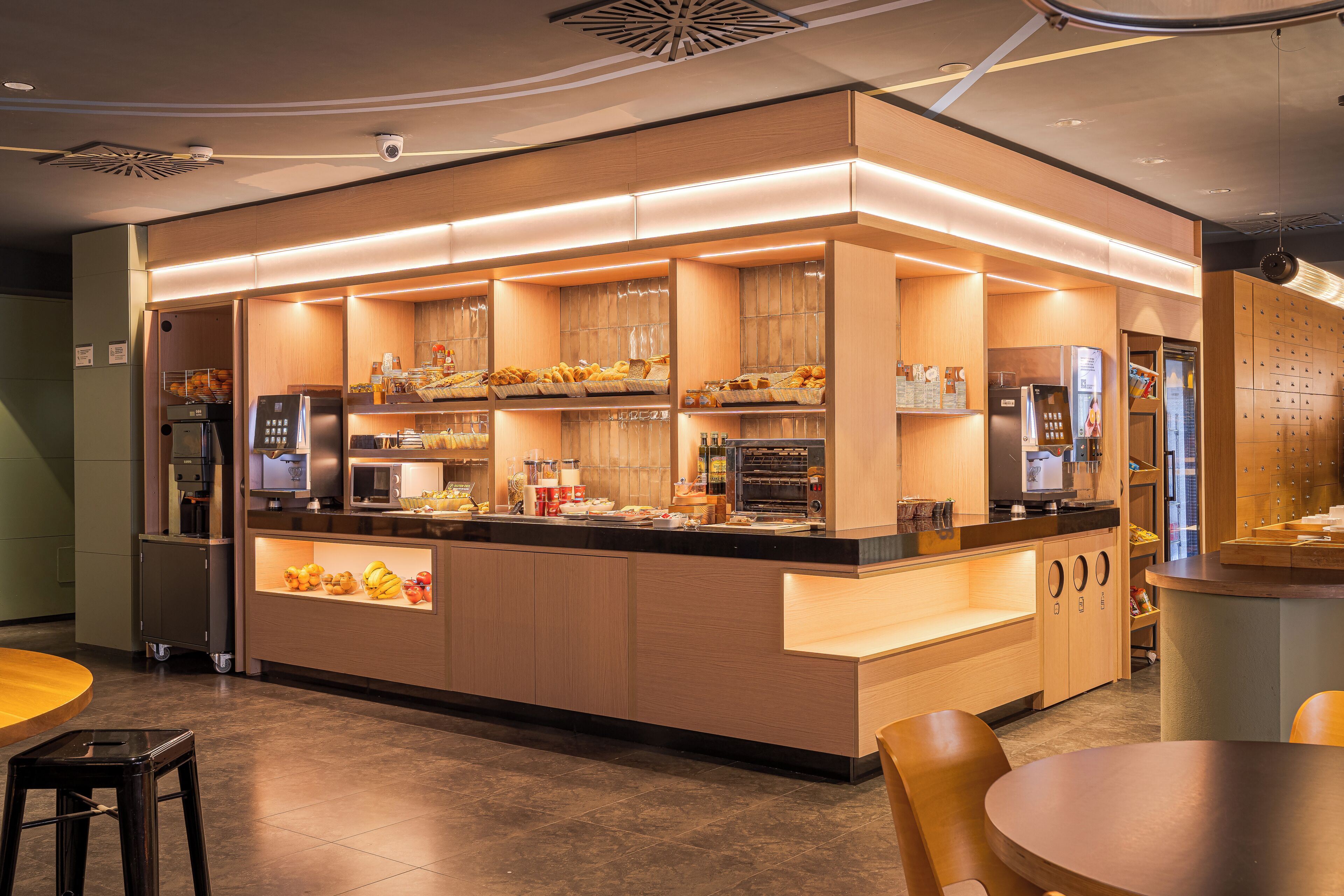 A modern kitchen with built-in appliances, a central island, and a seating area with stools.