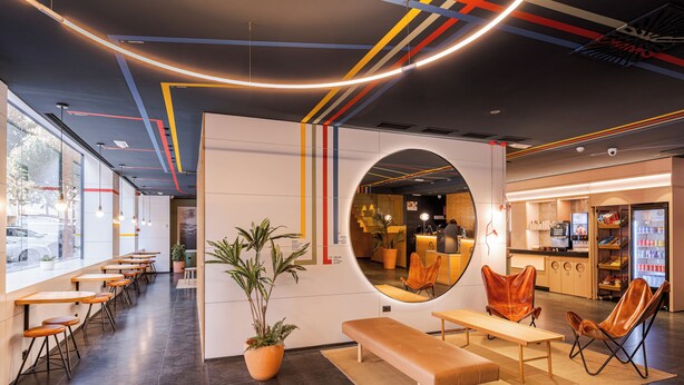 Een modern interieur met een lange toonbank, zithoek en een ronde spiegel.