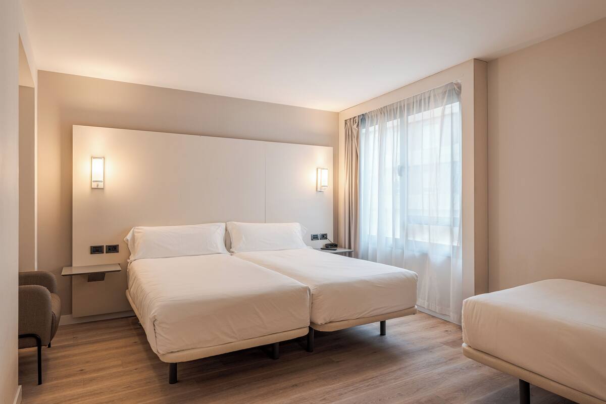 Habitación de hotel con cama doble, mesitas de noche, escritorio y una silla.