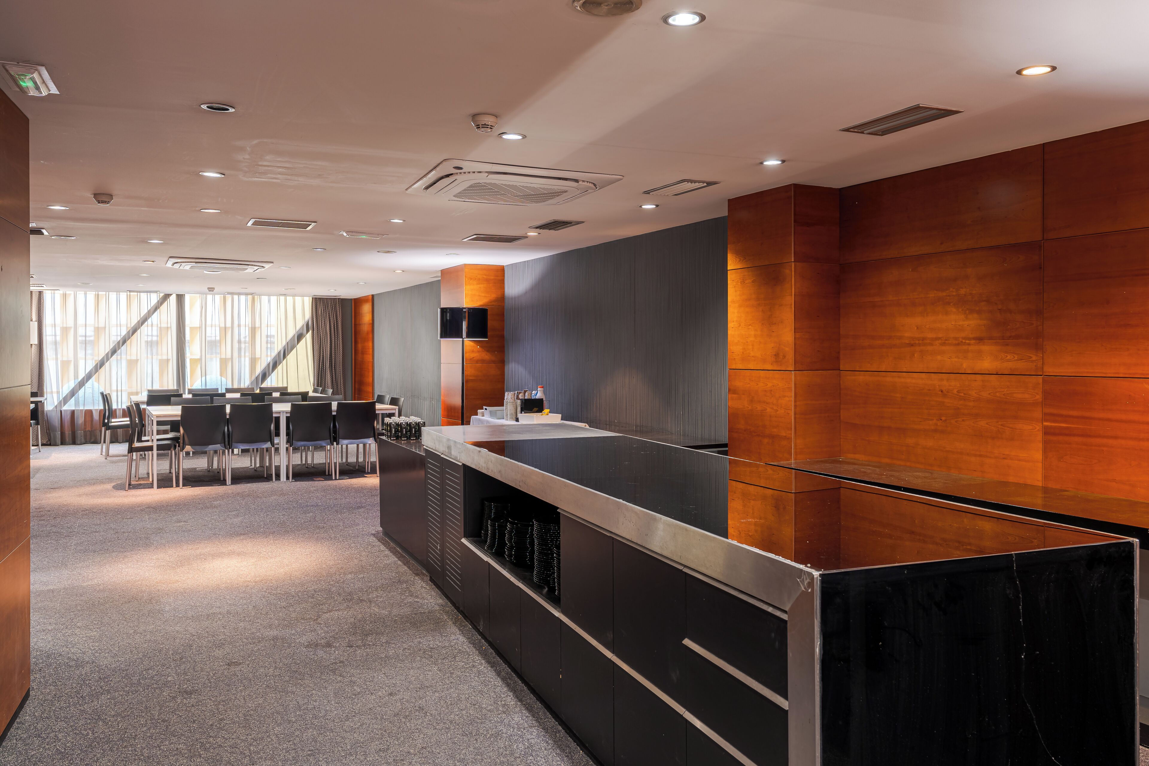 Een moderne hotellobby met een receptiebalie, een zithoek en grote ramen.