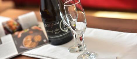 A bottle of wine and two glasses on a table with a menu and a napkin.