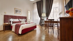 A hotel room with a large bed, a desk with chairs, a lamp, and a fruit bowl on the desk. - Hotel Suite Home Prague (Prague)