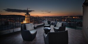A balcony with wicker furniture and a view of a cityscape at dusk. - Hotel Suite Home Prague (Prague)