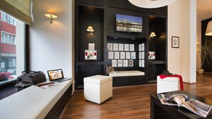 A modern hotel lobby with a seating area, a reception desk, and a television displaying a cityscape. - Hotel Suite Home Prague (Prague)