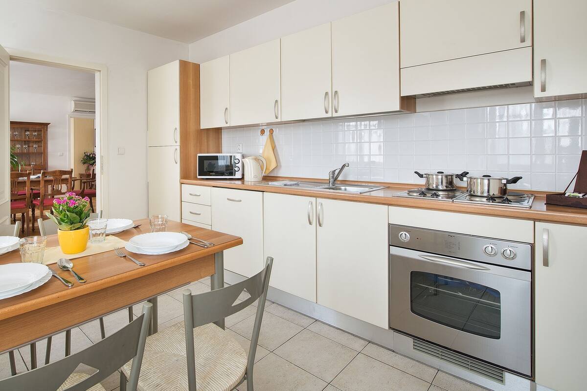 A modern kitchen with white cabinets, a wooden countertop, and stainless steel appliances.