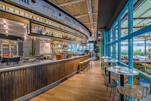A bar area with a curved counter, wooden flooring, and large windows offering a view of the outside.