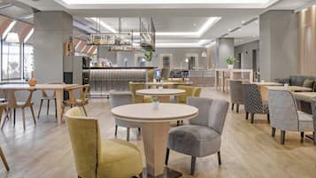 Relax in our stylish lobby, featuring a central bar, comfortable seating areas, and a spacious layout with high ceilings.