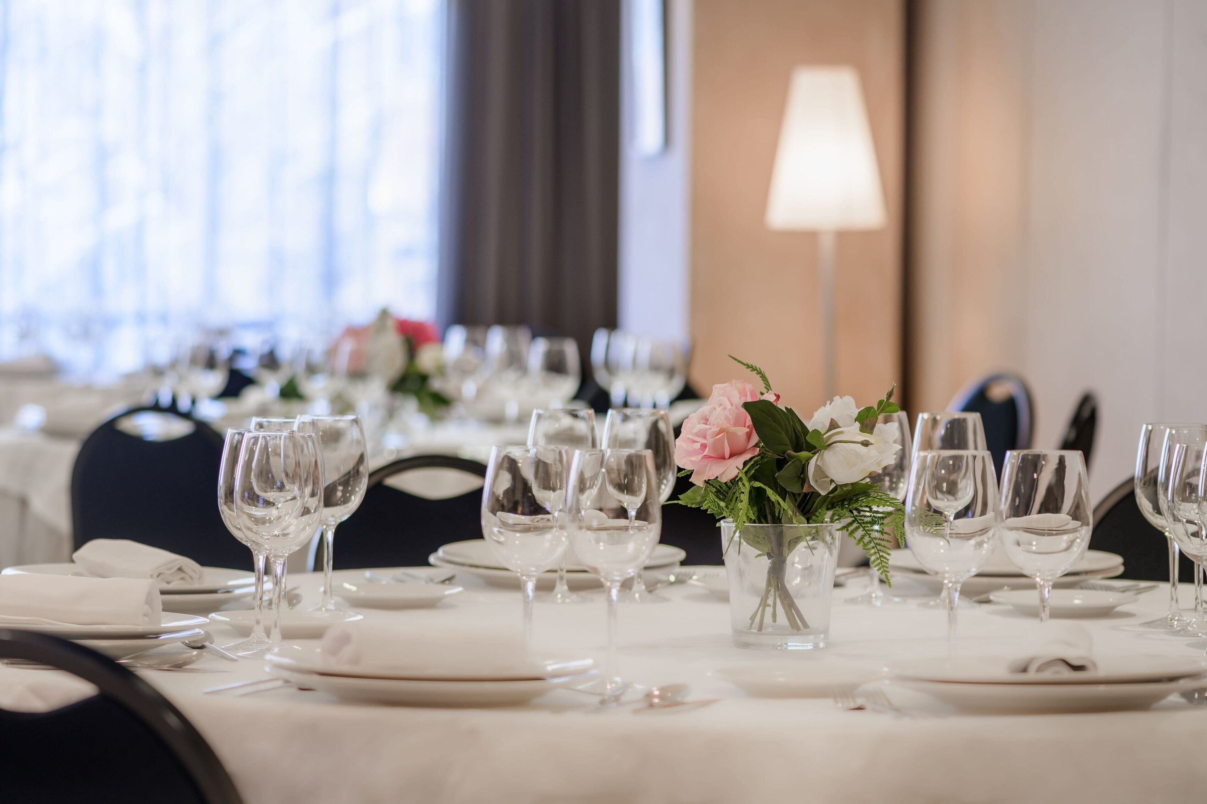 A dining table set with multiple wine glasses, plates, and a small vase with flowers.