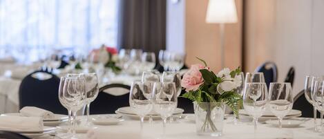 A dining table set with multiple wine glasses, plates, and a small vase with flowers.