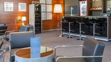 A modern hotel lobby with leather seating, a bar area, and a minibar.