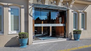 A hotel entrance with a glass door, two potted plants, and a clear view of the interior through the glass. - AC Hotel La Línea by Marriott (La Línea de la Concepción)