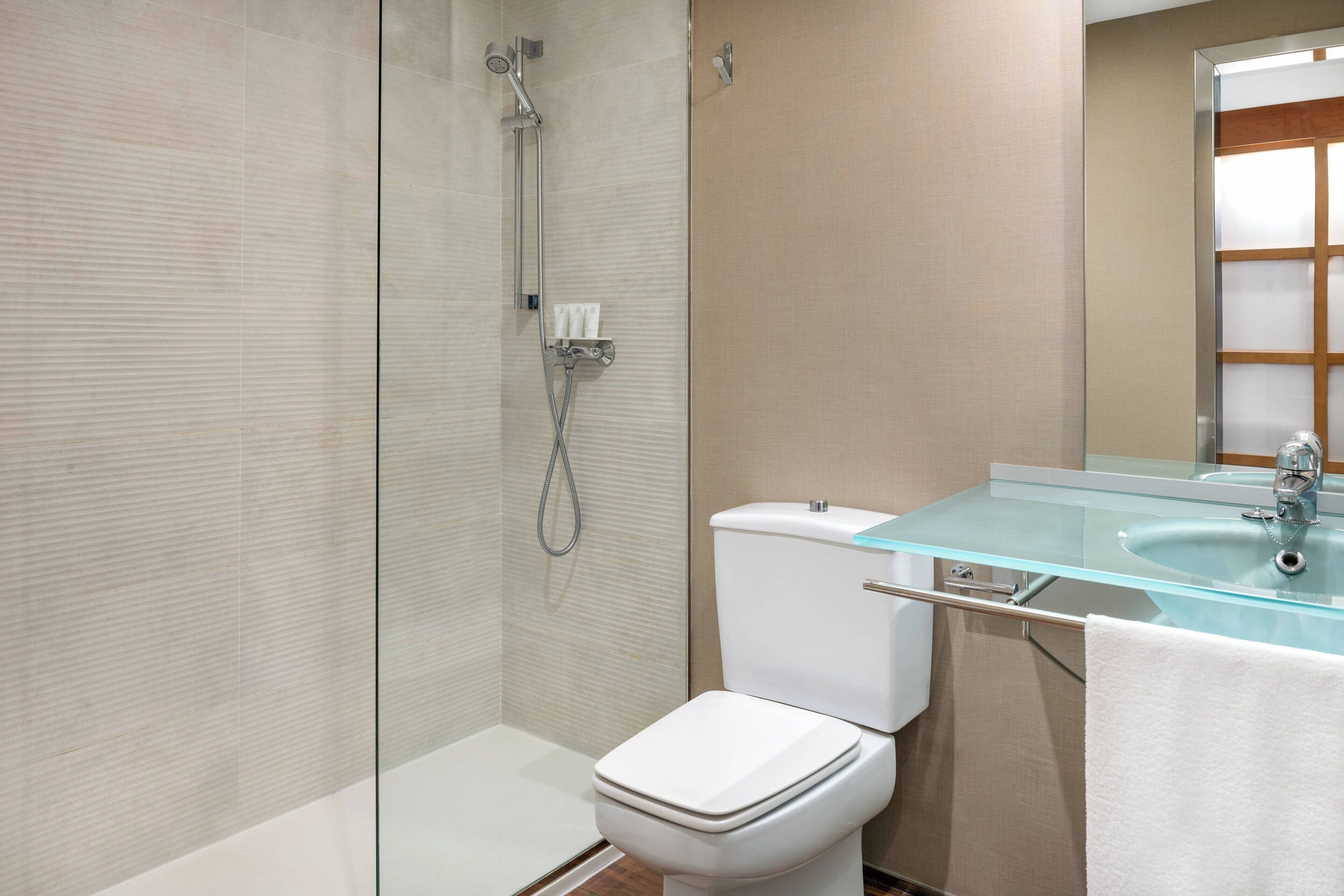 Un bagno moderno con cabina doccia in vetro, un water bianco e un lavandino in vetro.