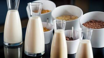 A variety of milk bottles and bowls with different contents, likely dairy products, arranged on a reflective surface.