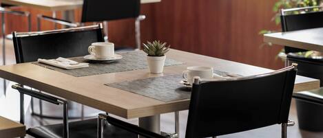 Un comedor moderno con una mesa de madera, sillas negras y una pequeña planta en maceta.