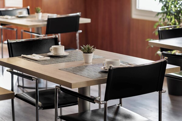 Un comedor moderno con una mesa de madera, sillas negras y una pequeña planta en maceta.