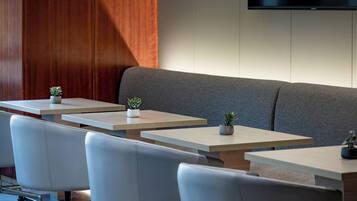 A modern seating area with a sofa and multiple tables, each with a small plant.