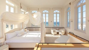 A bedroom with a canopy bed, a sitting area with a table and chairs, large windows with ocean views, and a balcony. - Grand Hotel Heiligendamm (Bad Doberan)