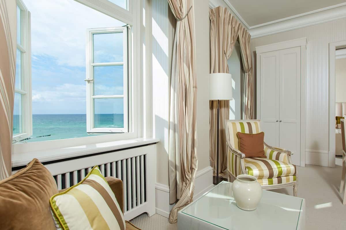 Une chambre avec vue sur l’océan, un coin repas et un espace salon avec des chaises à rayures.