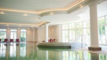 Una gran piscina interior con una isla central, zonas de estar y amplias ventanas.