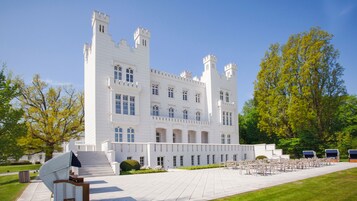 Um edifício grande e branco, com estilo de castelo, com várias torres e janelas em arco.
