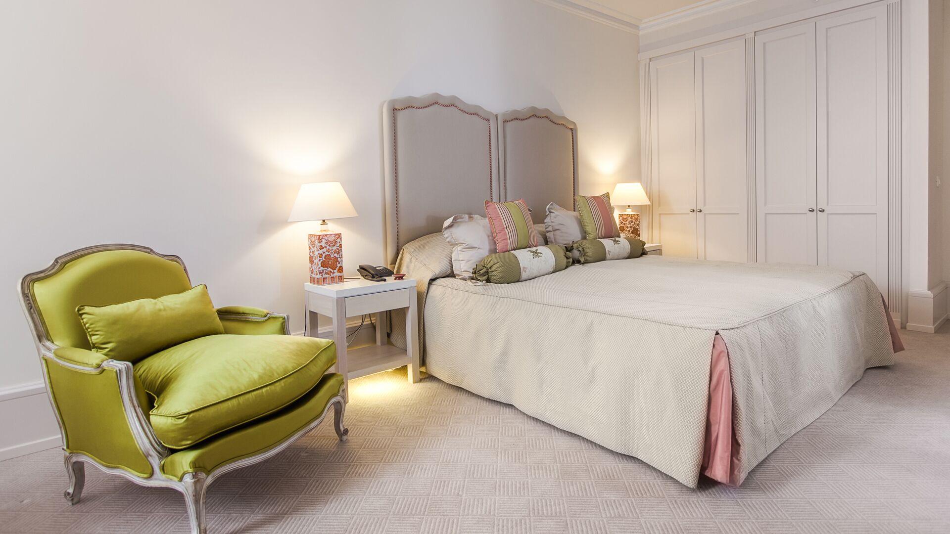 Un dormitorio con cama, una silla, una mesita de noche, una lámpara y un armario.