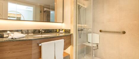A modern bathroom with a glass-enclosed shower, a large mirror, and a wooden vanity.