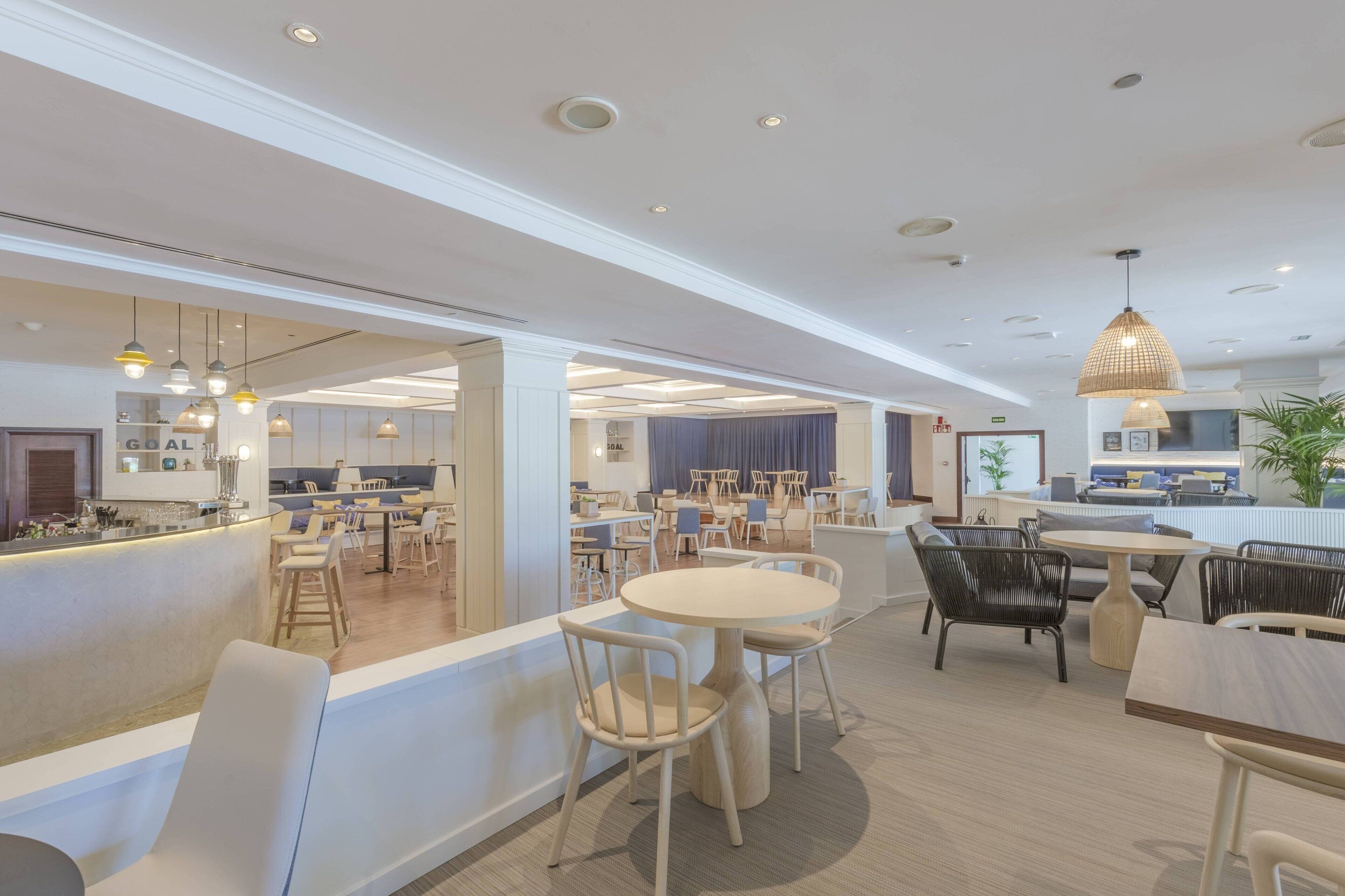 A modern hotel lobby with a bar area, seating arrangements, and a view into the dining area.