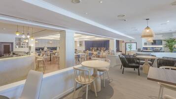 Een moderne hotellobby met een bar, zitgedeeltes en zicht op het eetgedeelte.
