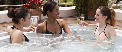 Un jacuzzi con tres personas brindando con champán.