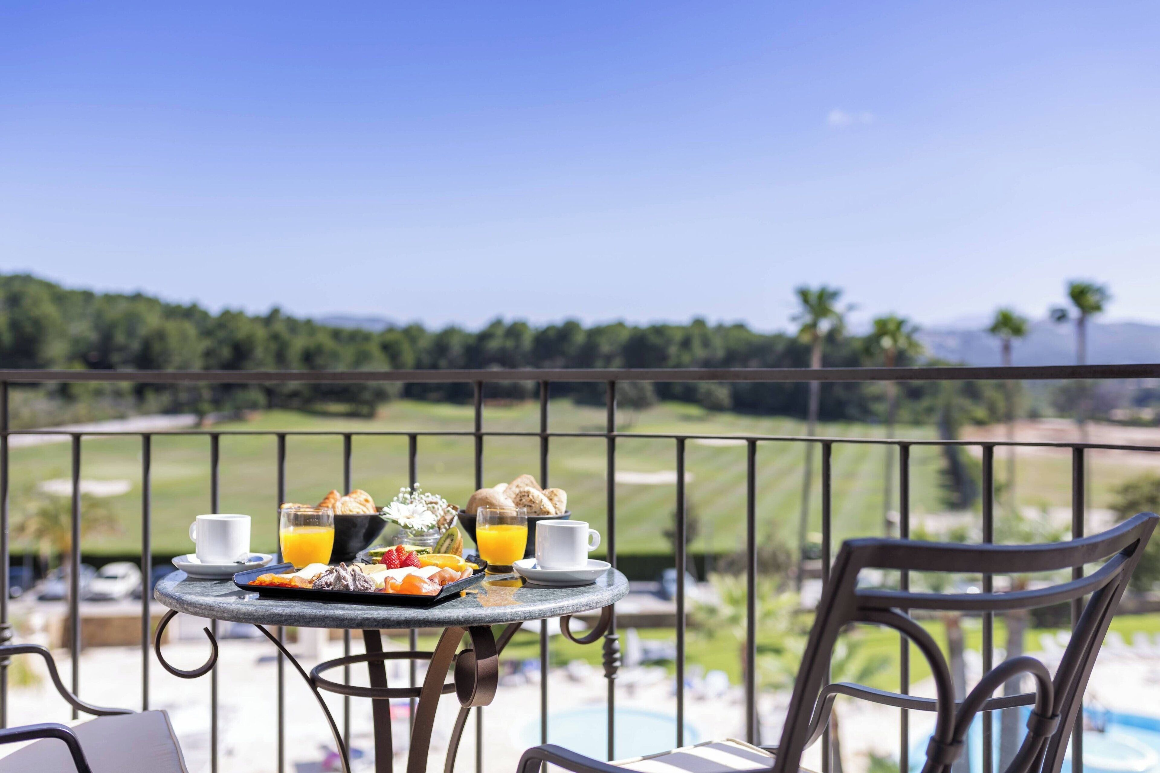 A dining table with breakfast items and a view of a golf course.