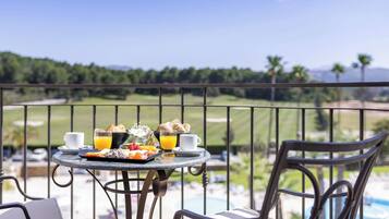 A dining table with breakfast items and a view of a golf course.