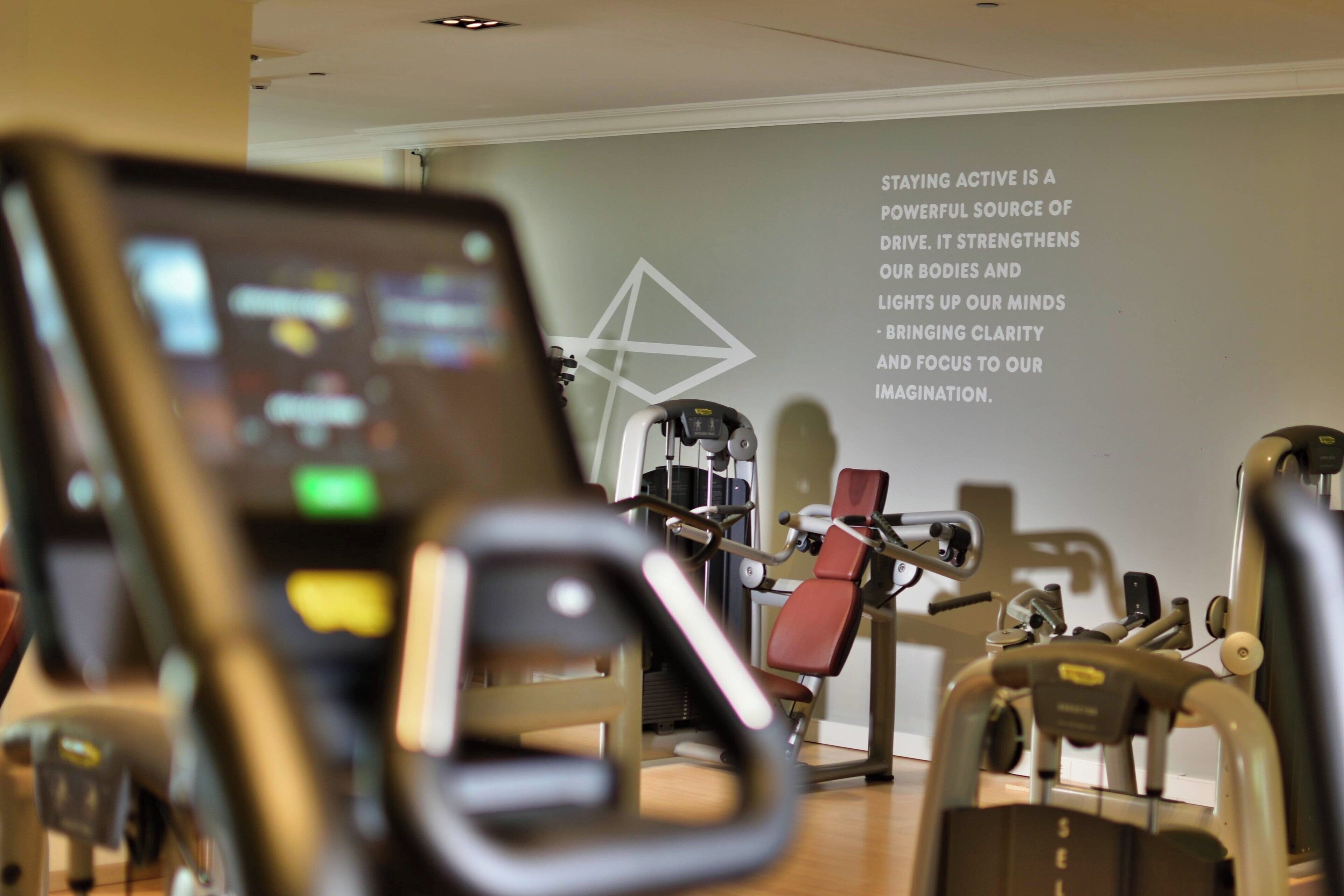 A gym with exercise equipment and a motivational quote on the wall.
