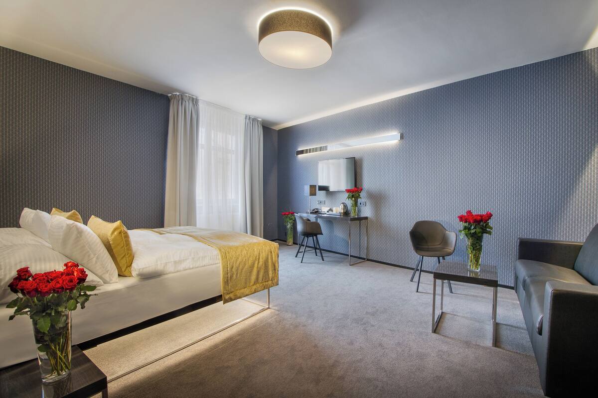 A modern hotel room with a bed, a desk, and a chair.