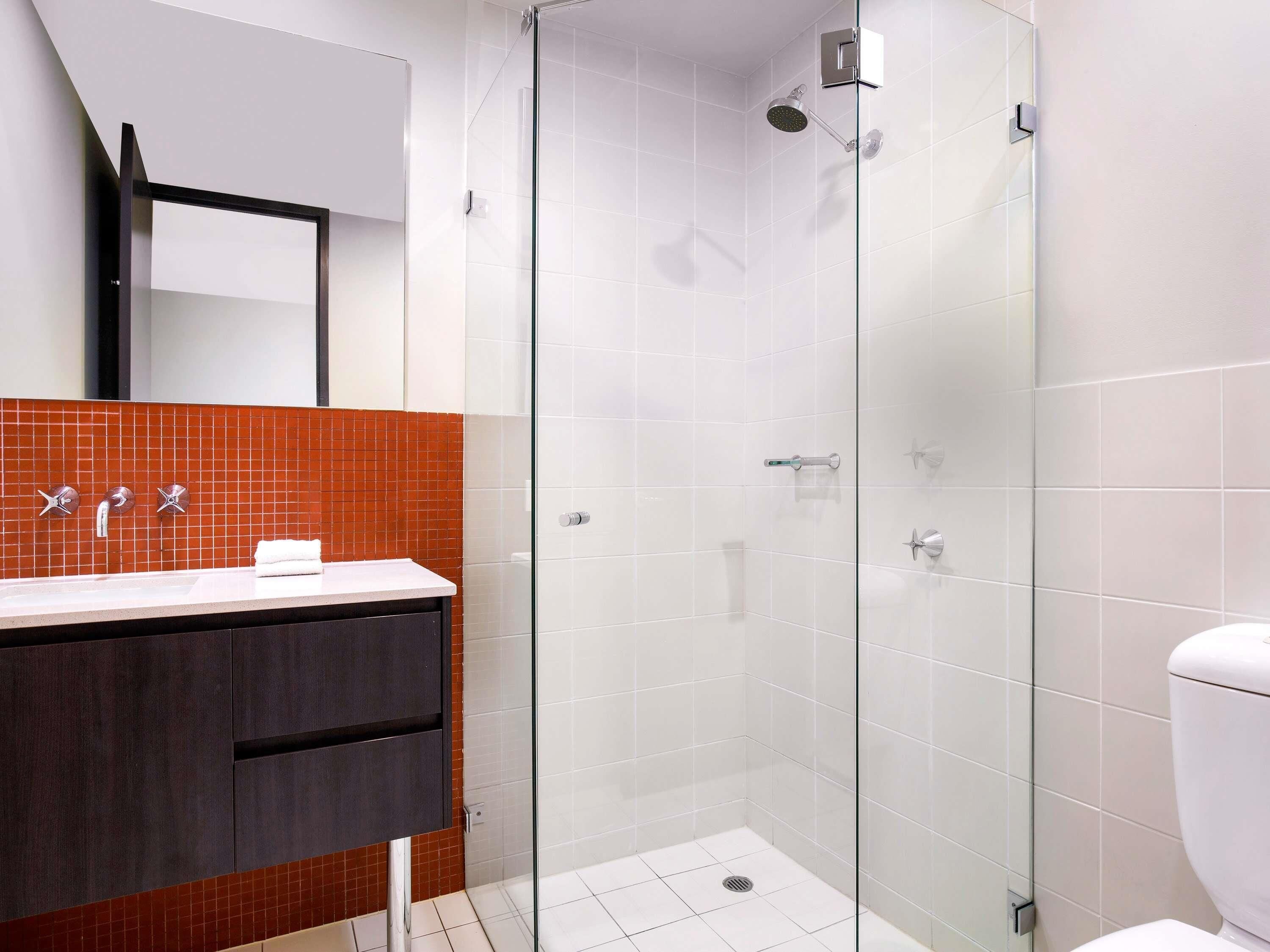 A modern bathroom with a glass shower enclosure, a white toilet, and a vanity with a mirror.