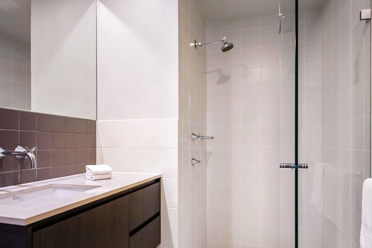 A modern bathroom with a glass-enclosed shower, a vanity with a sink, and a towel rack.