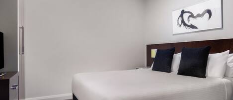 A hotel room with a bed, a television, a dresser, and a painting on the wall.