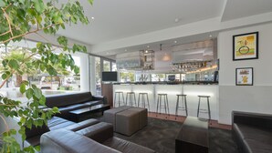 Un área de bar moderna con taburetes, una barra y un televisor.