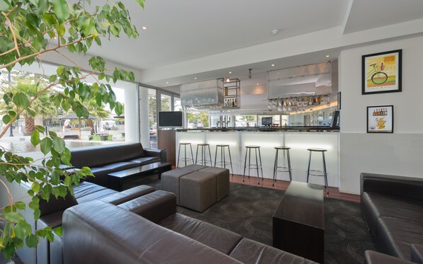 A modern bar area with stools, a counter, and a television. - Scenic Hotel Te Pania (Napier)