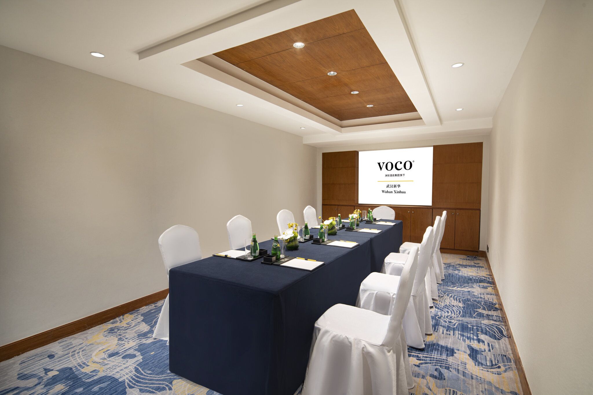A conference room with a long table, white chairs, and a projection screen displaying "VOCO".