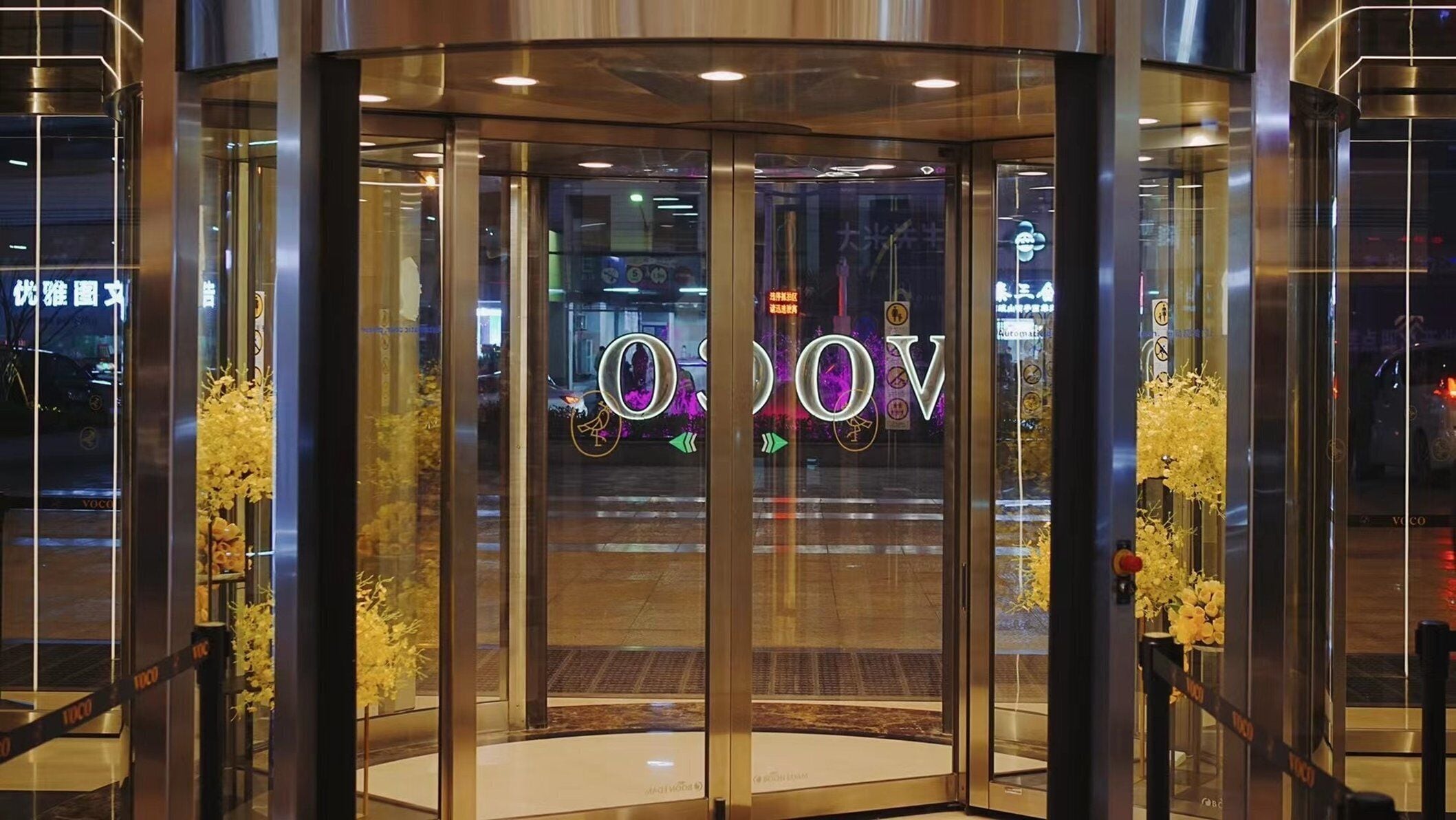 Una puerta giratoria con barrera de cristal y un cartel con letras iluminadas.