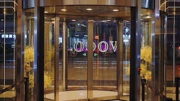Una puerta giratoria con barrera de cristal y un cartel con letras iluminadas.