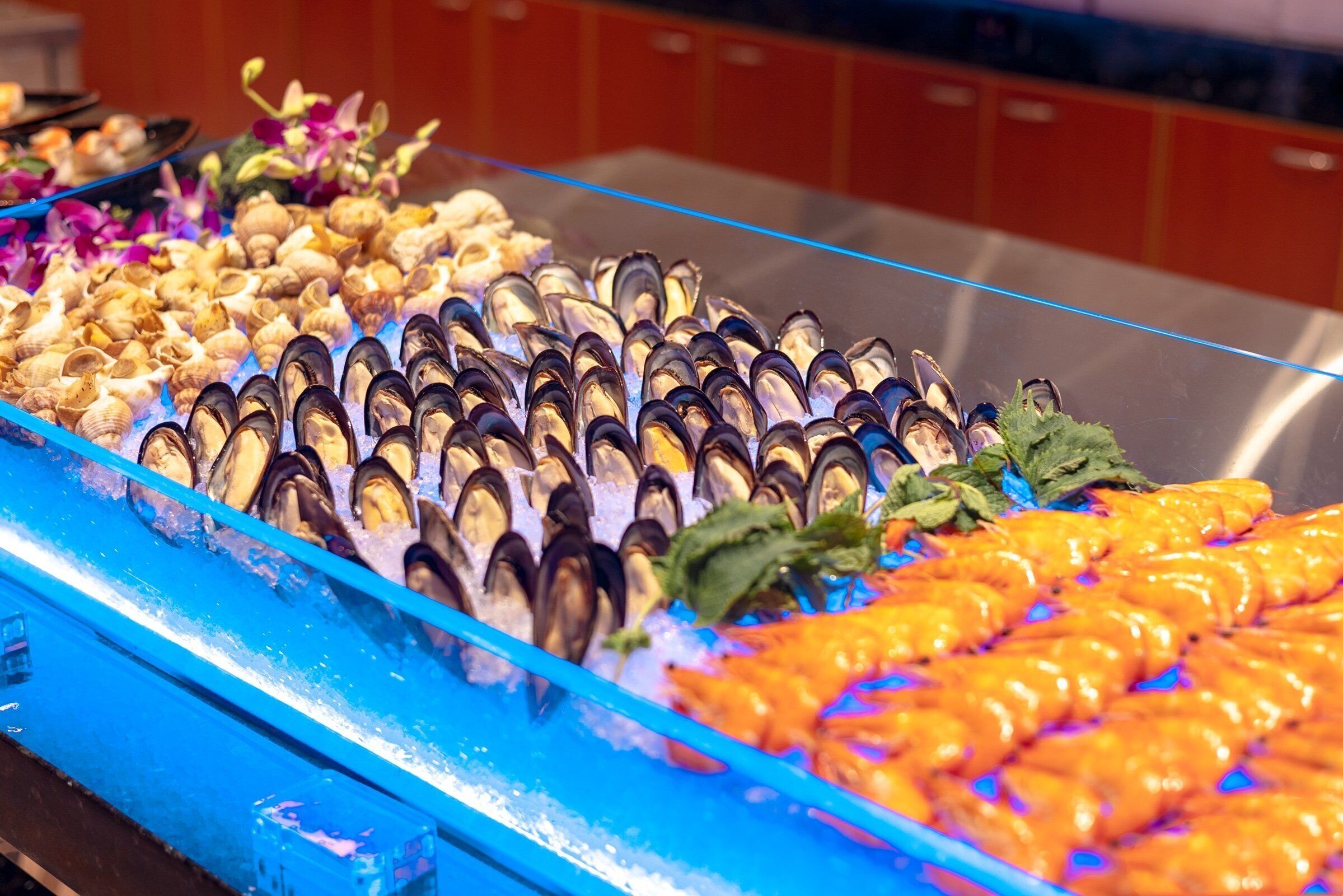 A seafood display with mussels, oysters, and shrimp on ice.