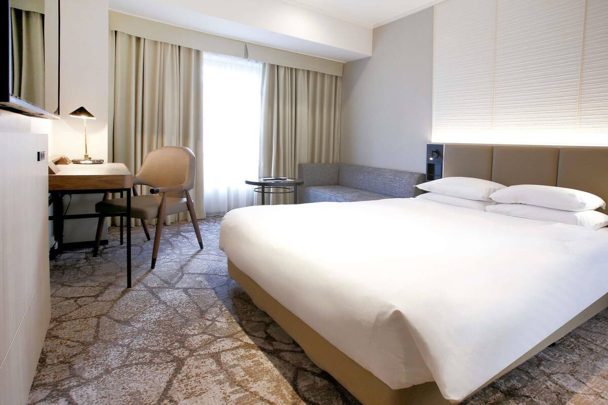 Ein Hotelzimmer mit Bett, Schreibtisch, Stuhl und einem kleinen Tisch.