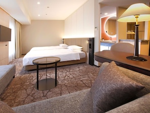 A hotel room with a bed, a small table, a sofa, and a lamp.