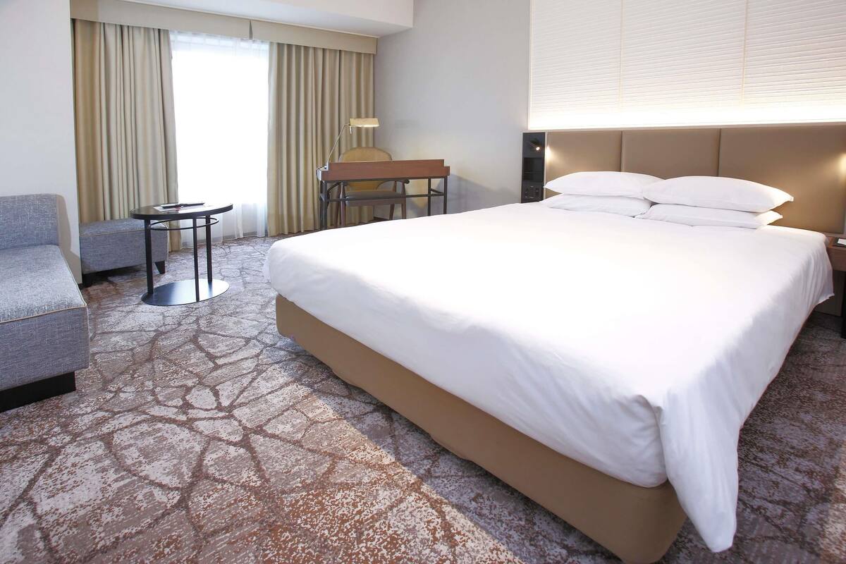 Ein Hotelzimmer mit einem großen Bett, einem Schreibtisch, einem Sessel und einem Schlafsofa.